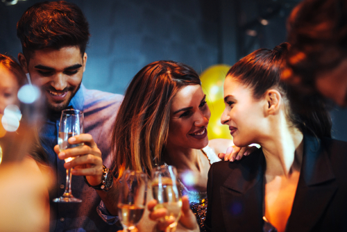 3 young people in a bar.  2 people are speaking to each other